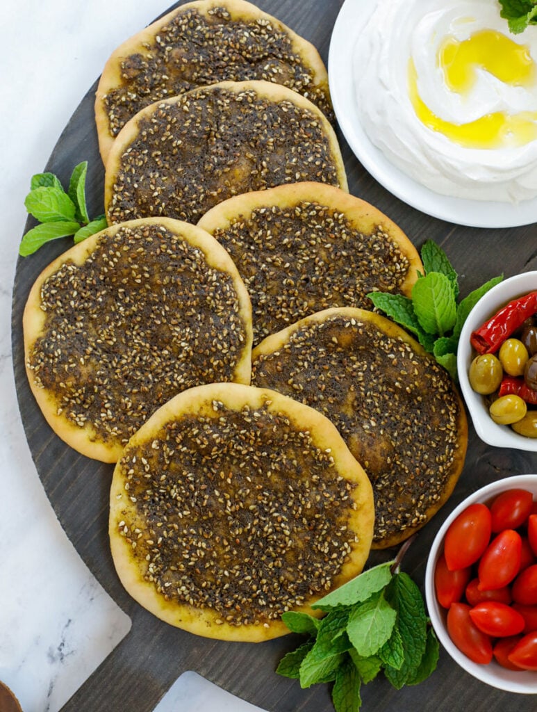 top down shot of the zaatar manakeesh on a dark board served with labneh