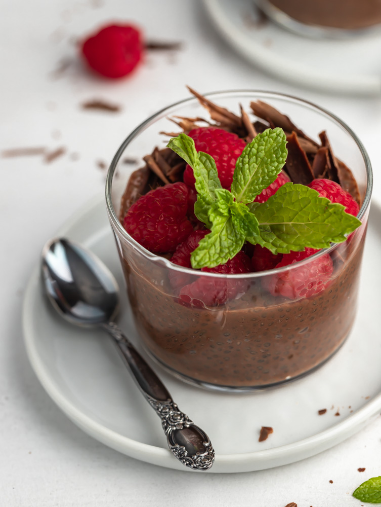 chocolate chia pudding cups in a plate with a spoon next to it.