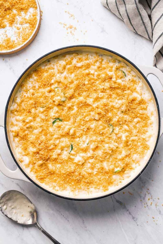 jalapeno mac and cheese in a skillet topped with bread crumbs before baking