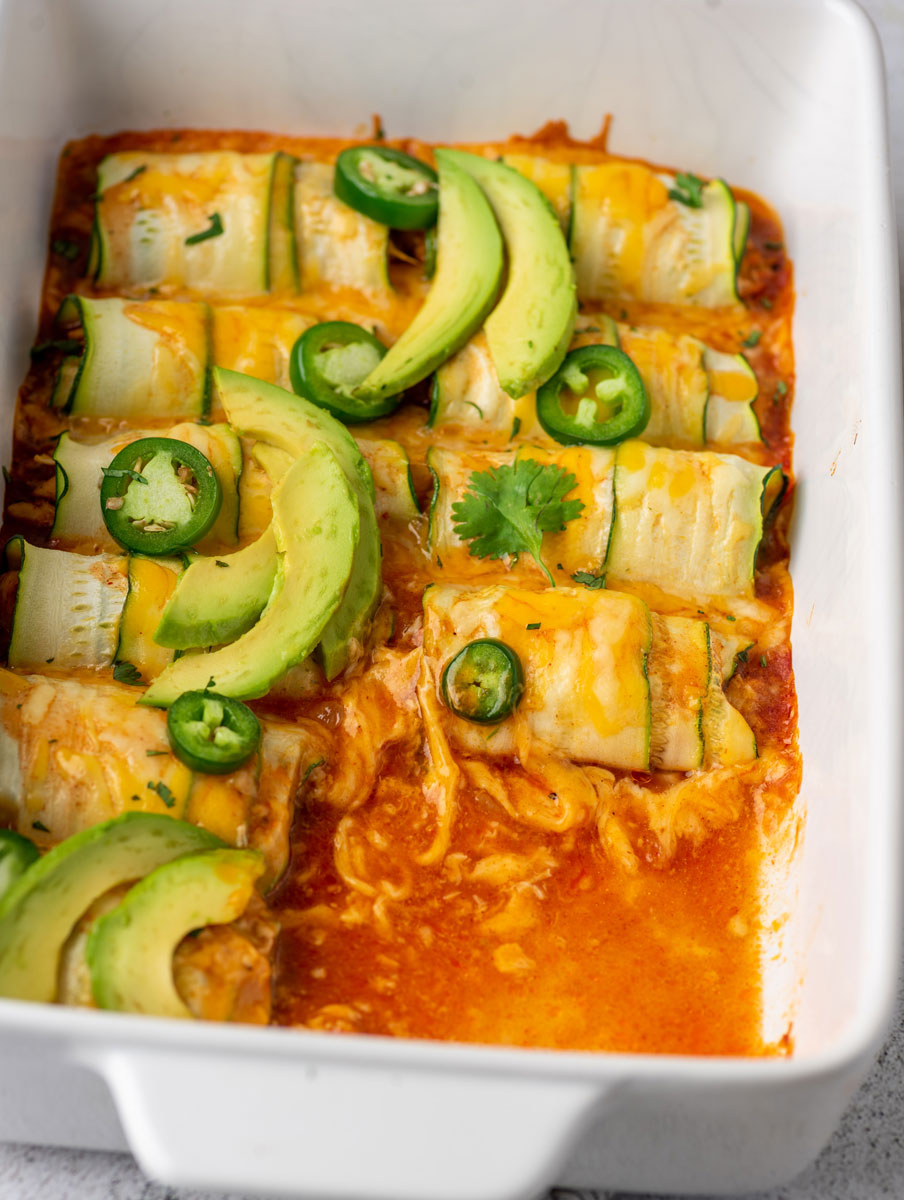chicken enchiladas in a baking dish after baking with few pieces removed from the dish
