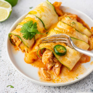 a fork cutting into a piece of chicken zucchini enchiladas