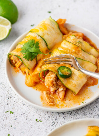 a fork cutting into a piece of chicken zucchini enchiladas