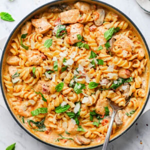 creamy mushroom chicken pasta in a skillet garnished with basil