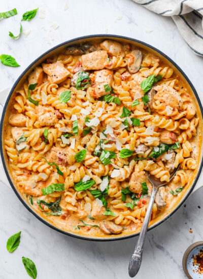 creamy mushroom chicken pasta in a skillet garnished with basil