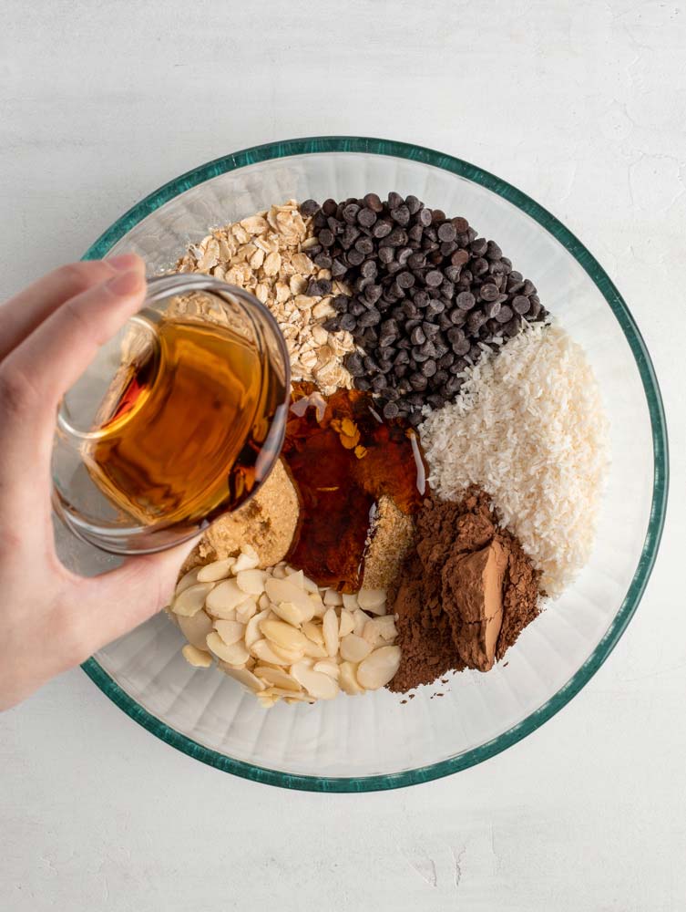 maple syrup being pour into a bowl with all the ingredients