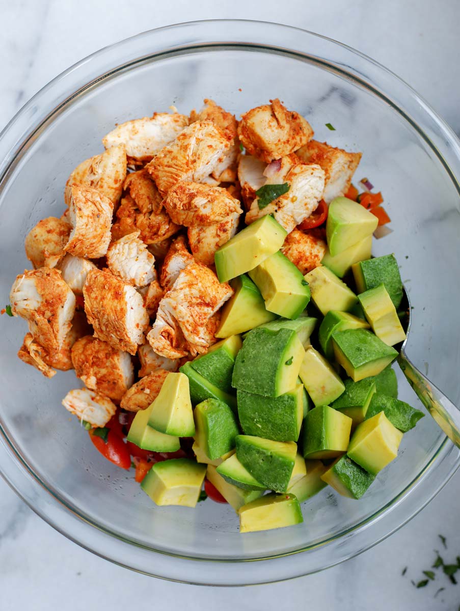 A bowl with the ingredients needed to make an avocado chicken salad.