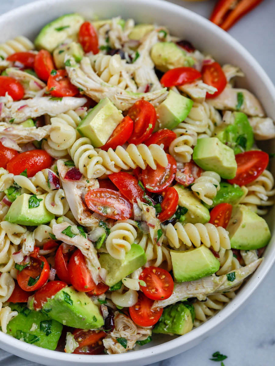 Close up of a bowl of avocado chicken pasta salad.