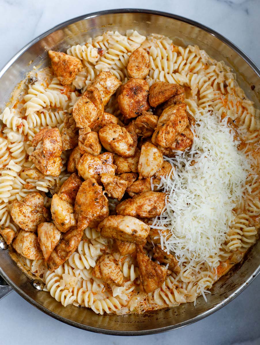 Chicken and cheese added to the pan of cajun pasta.