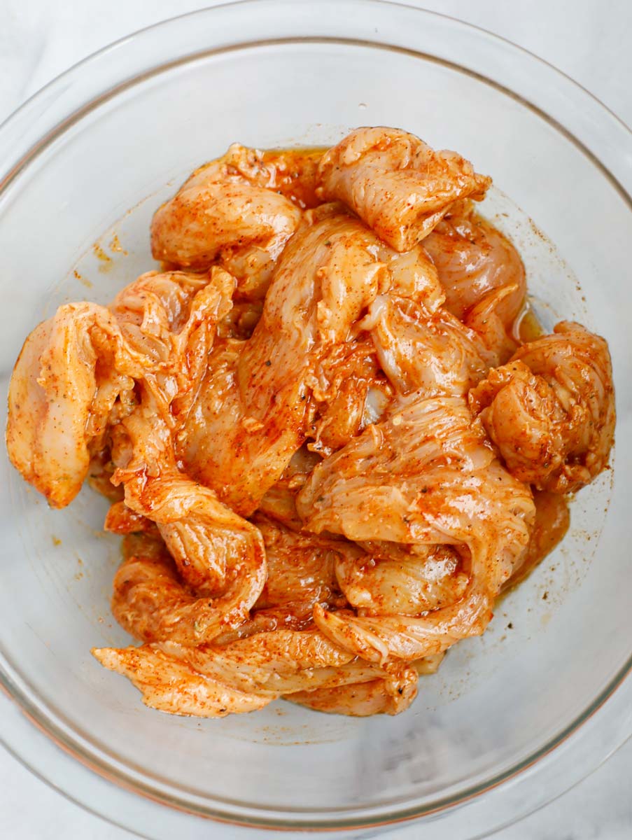 Chicken being marinaded in a bowl.