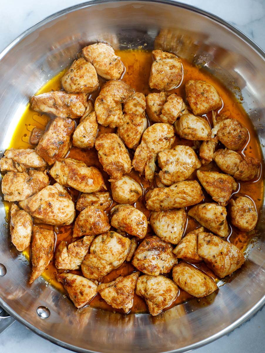 Cooked chicken cubes in a pan.