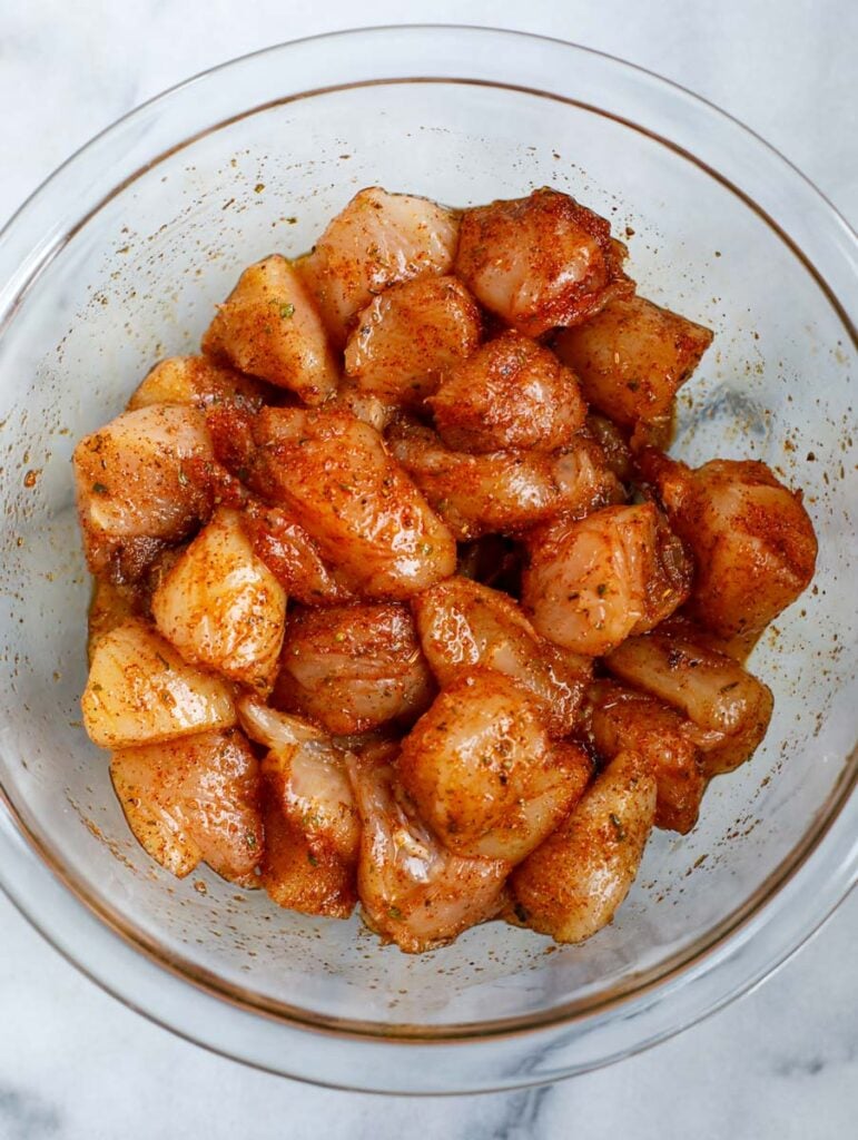 Seasoned marinating chicken cubes in a bowl.