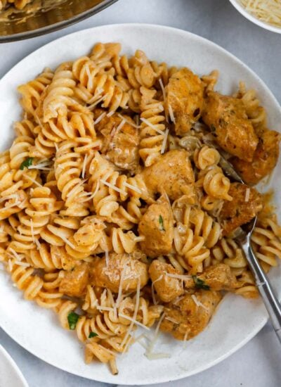 A bowl of creamy cajun chicken pasta with a fork inside.