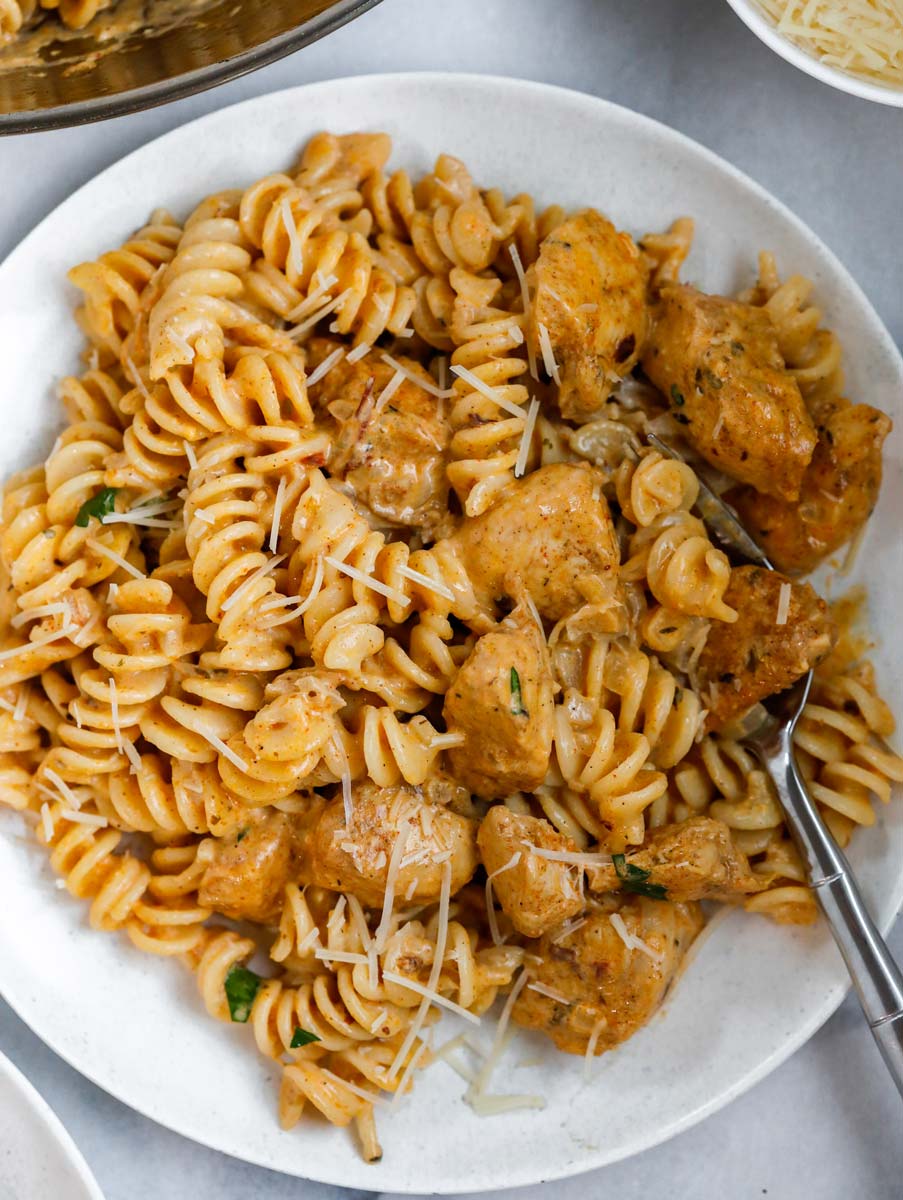 A bowl of creamy cajun chicken pasta with a fork inside.