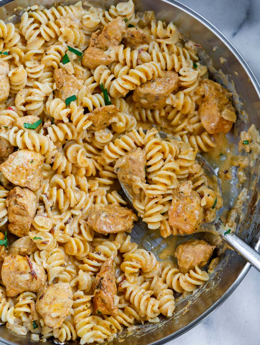 Close up of creamy cajun pasta with a spoonful of pasta and chicken.