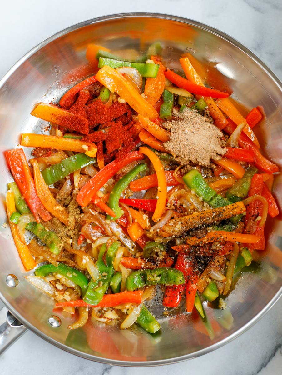 Seasoning added to a skillet of vegetables.