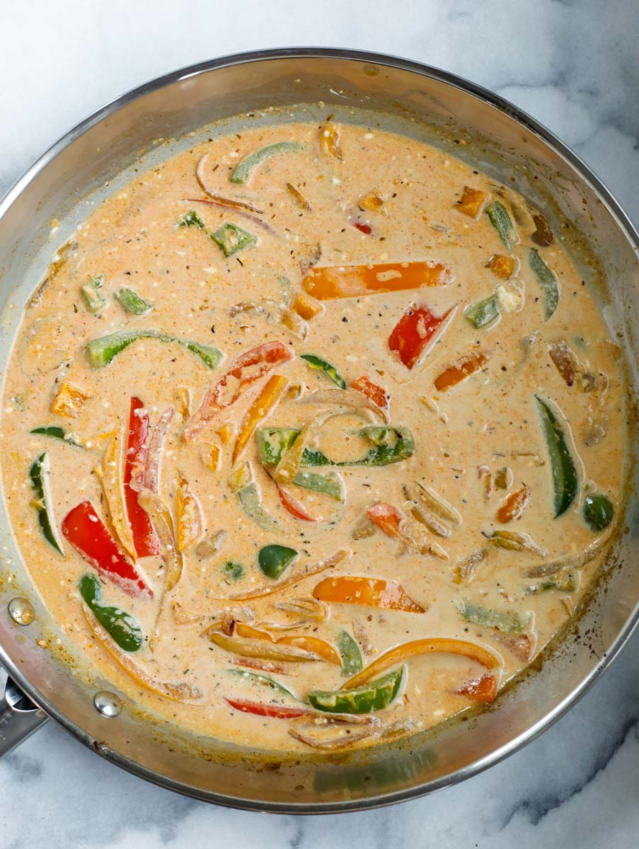 Cream sauce being made in the skillet of vegetables.