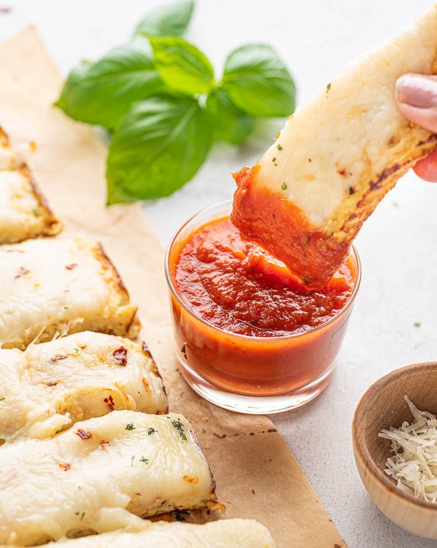 piece of cauliflower breadstick being dipped in marinara sauce