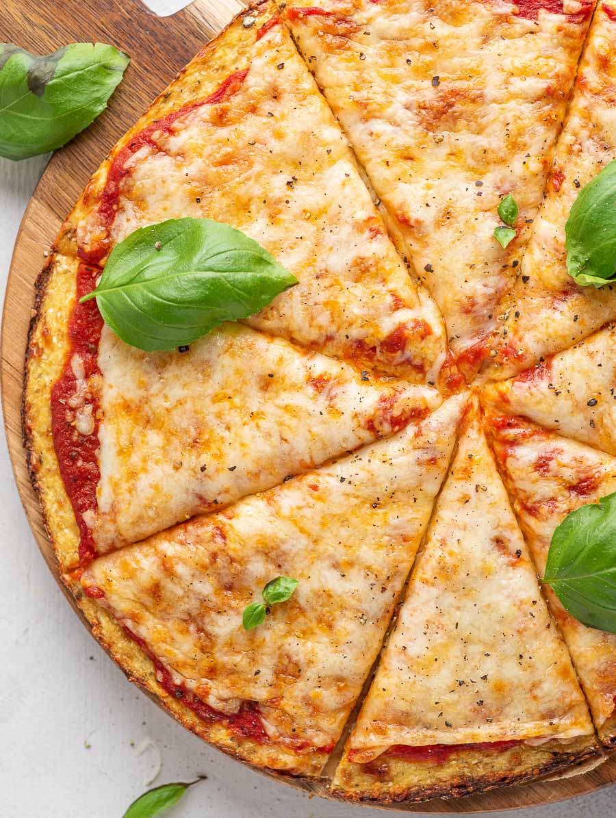 top down shot of cauliflower pizza with basil leaves on top