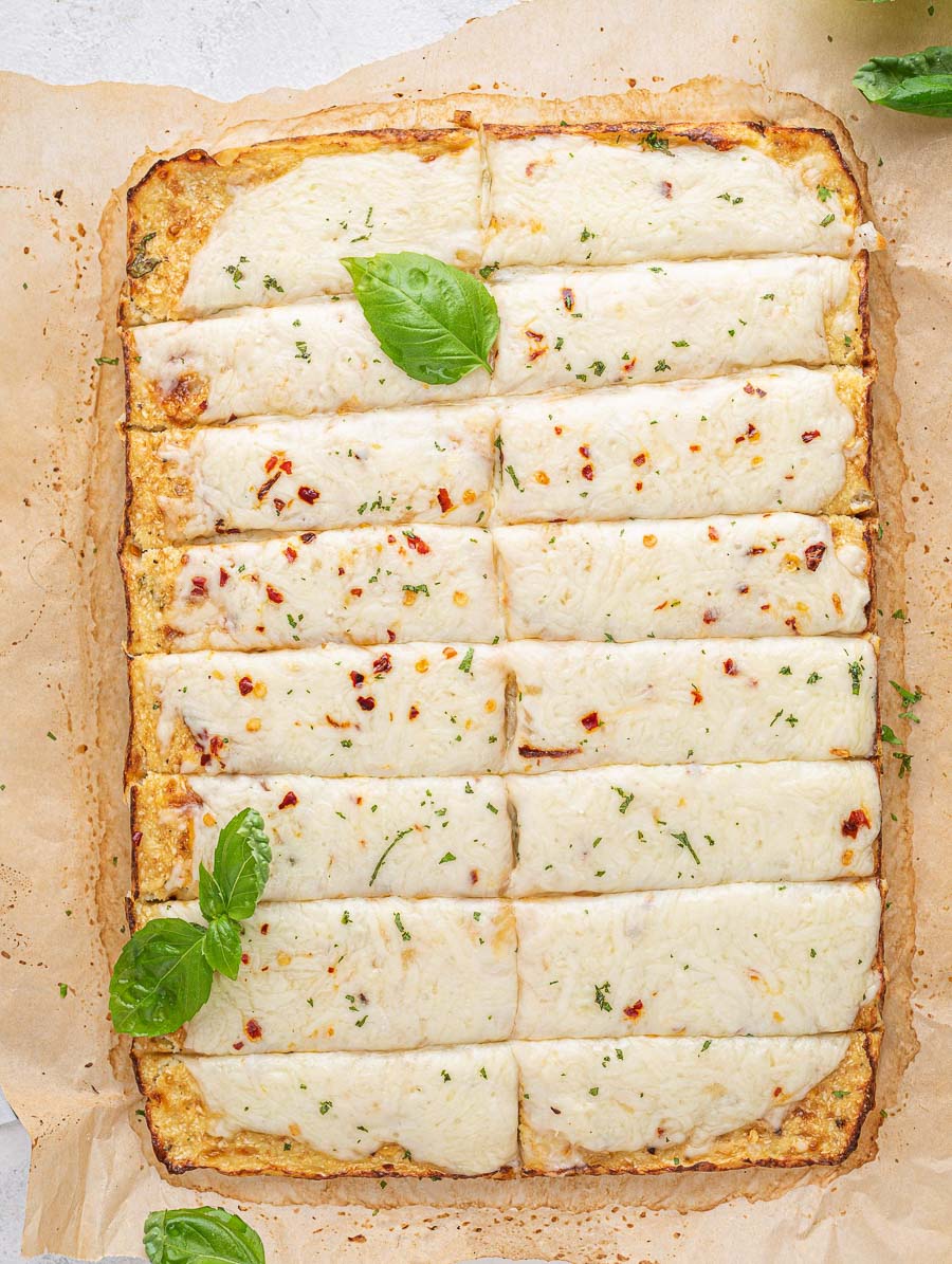 top down shot of cauliflower bread sticks with basil leaves on top