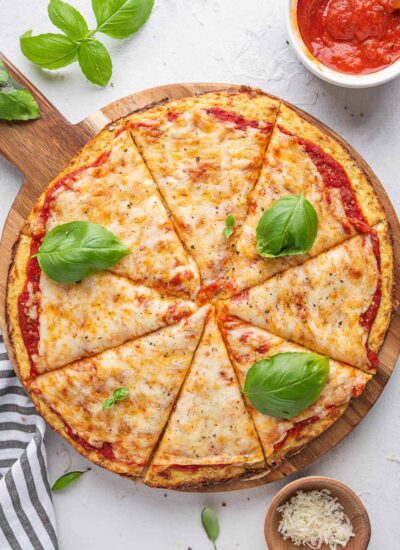 top down shot of cauliflower pizza with basil leaves on top