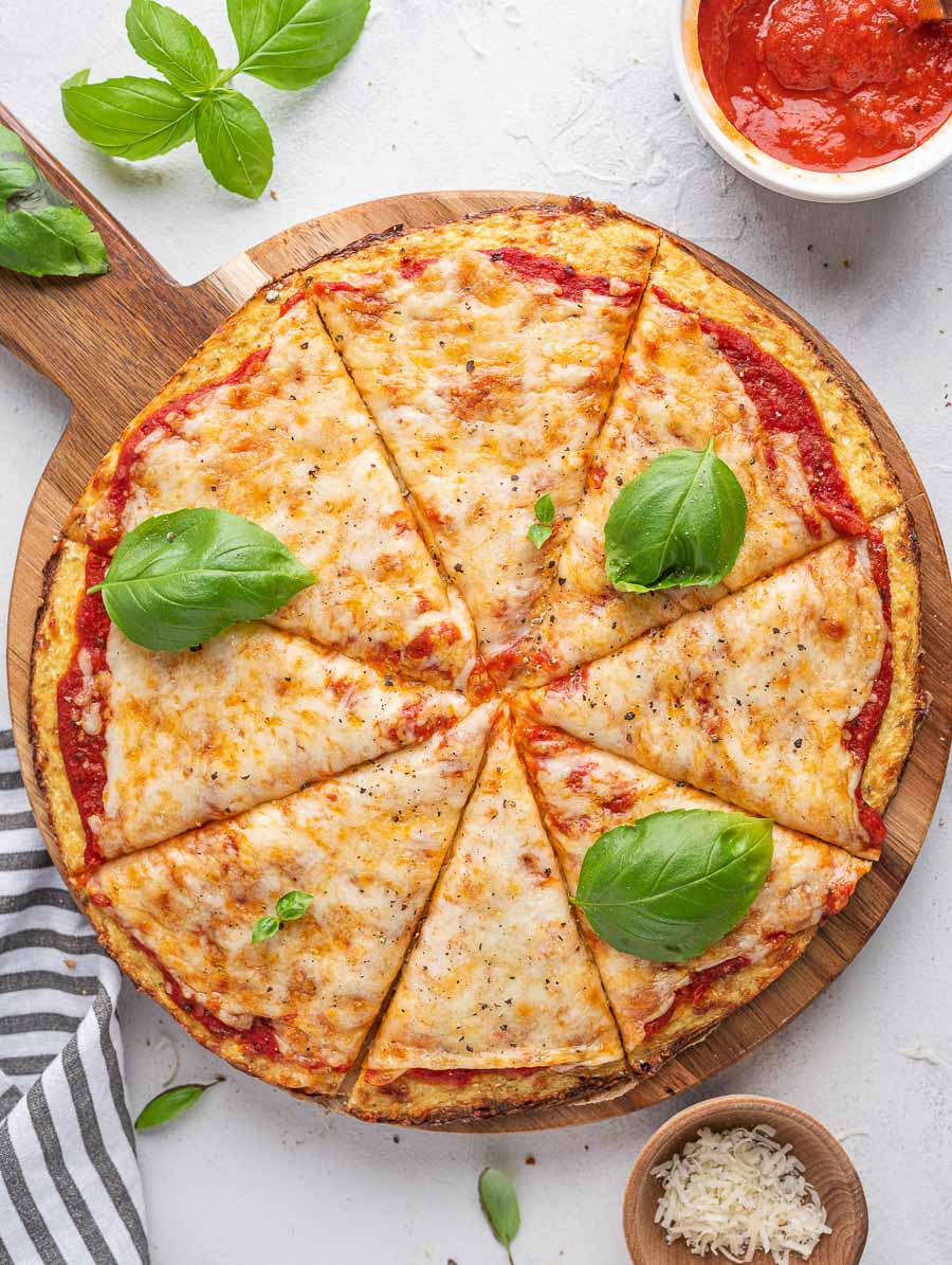 top down shot of cauliflower pizza with basil leaves on top