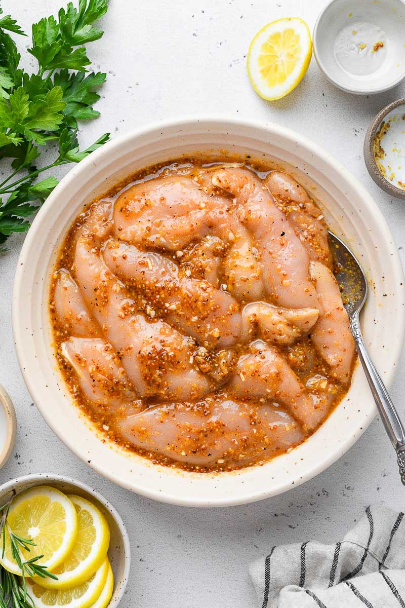 Bowl of chicken tenders marinaded in honey mustard sauce.