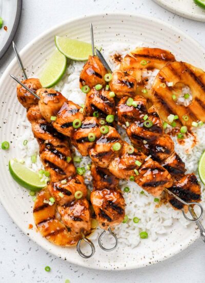 Hawaiian chicken skewers on a plate over rice.