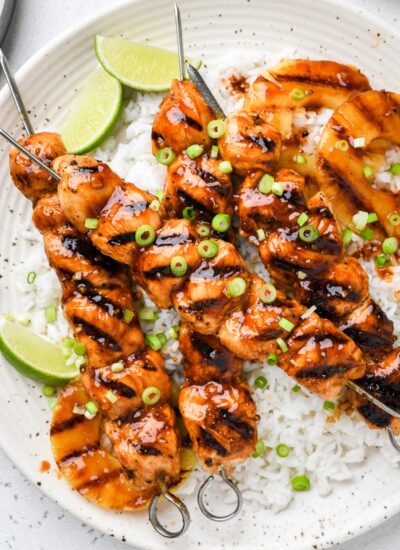 Hawaiian chicken skewers on a plate over rice.