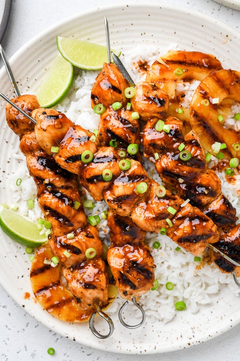 Hawaiian chicken skewers on a plate over rice.