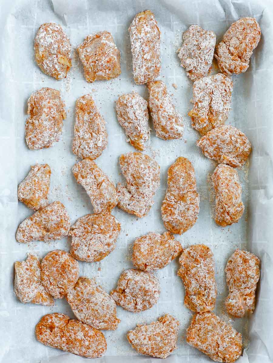 chicken bites before baking lined on a baking sheet.