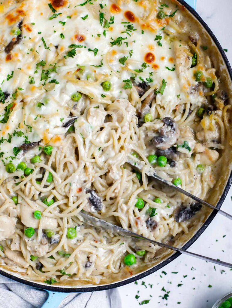 A pan of chicken tetrazzini with a pair of tongs stuck in.