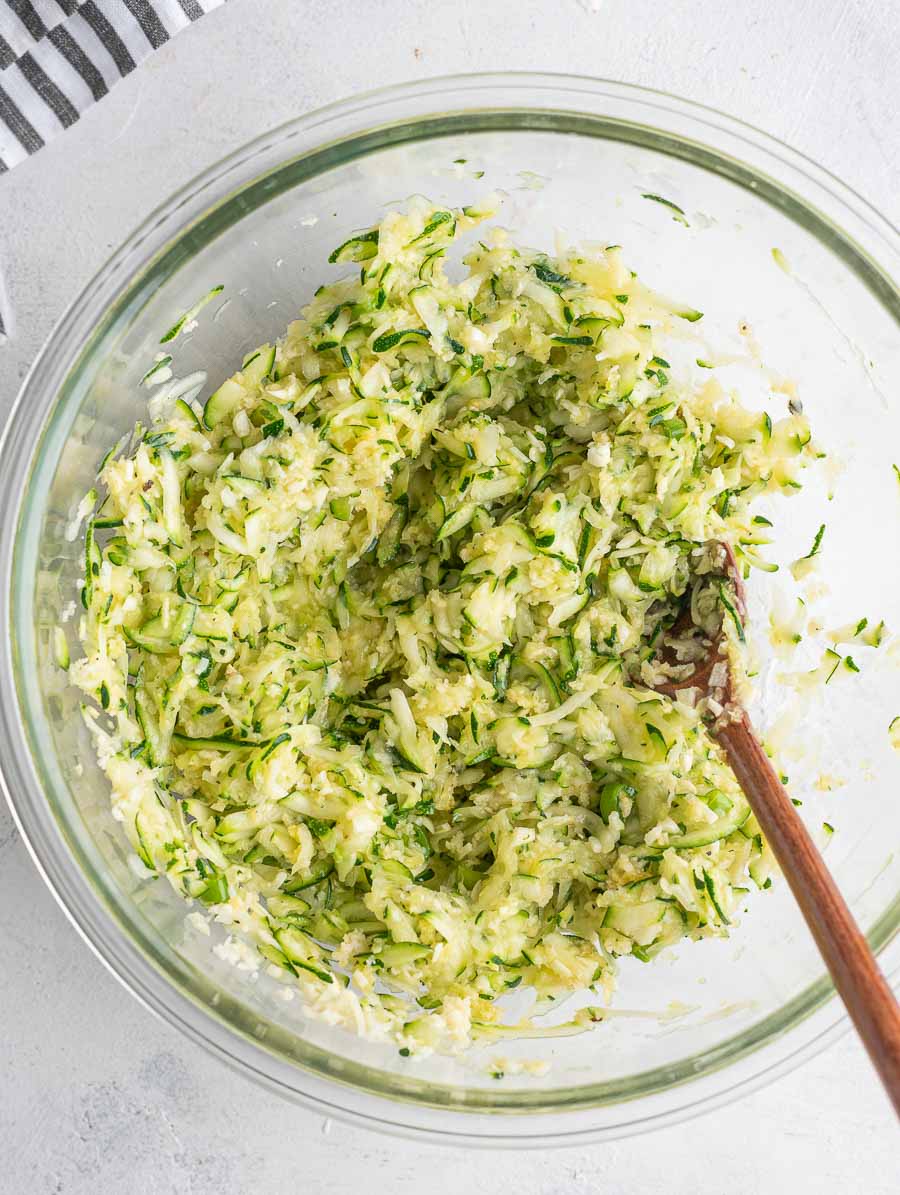 shredded zucchini in a glass bowl after being mixed with other ingredients