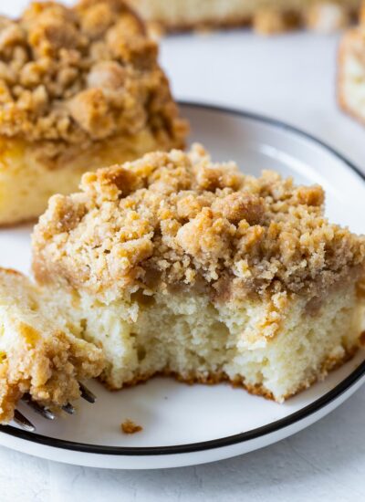 a piece of apple crumb cake on a plate with a bite taken out of it.