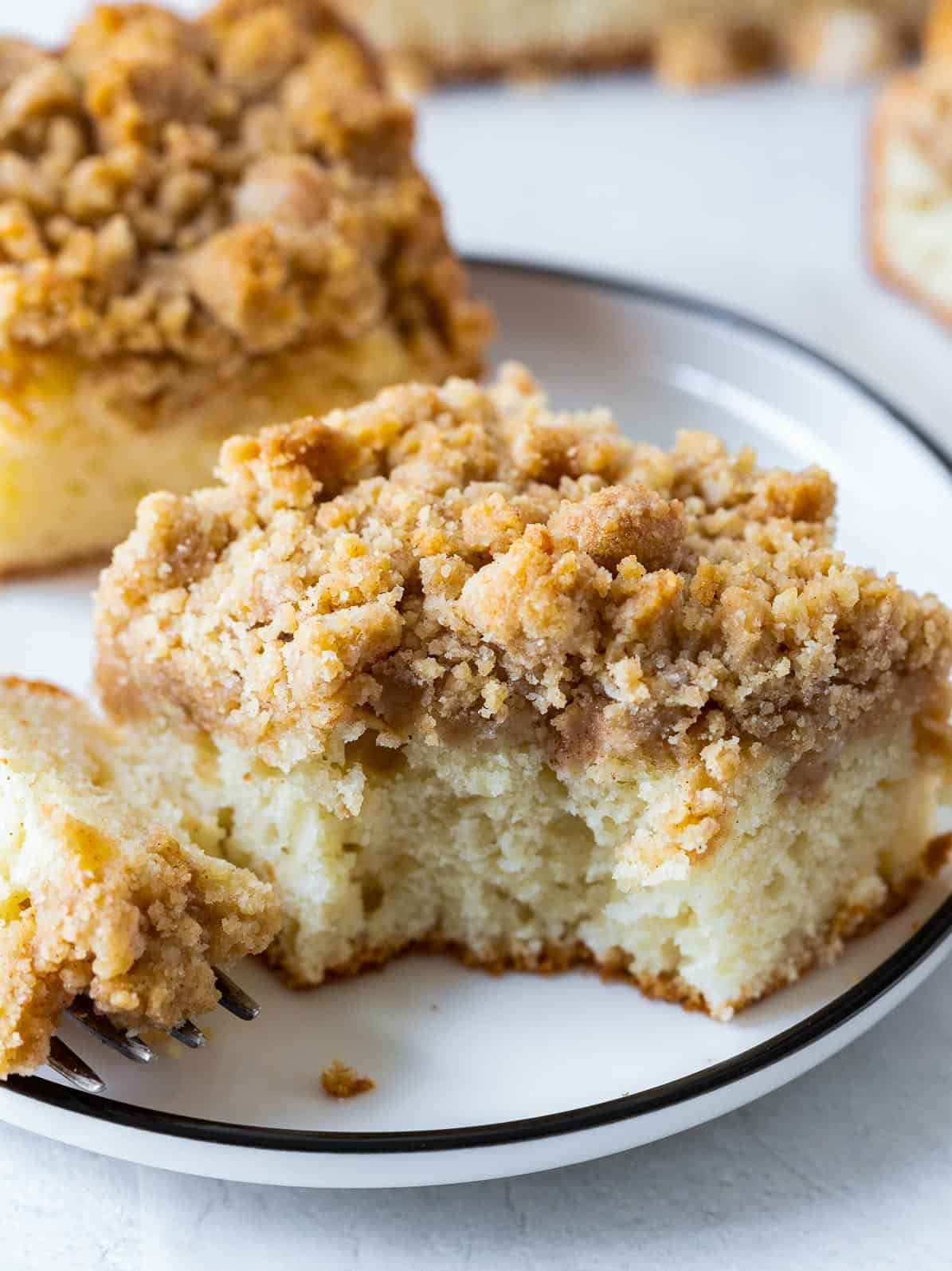 a piece of apple crumb cake on a plate with a bite taken out of it.