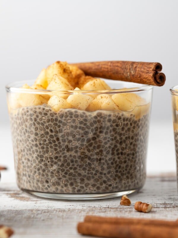 Overnight Chia Pudding topped with apples and a cinnamon stick.