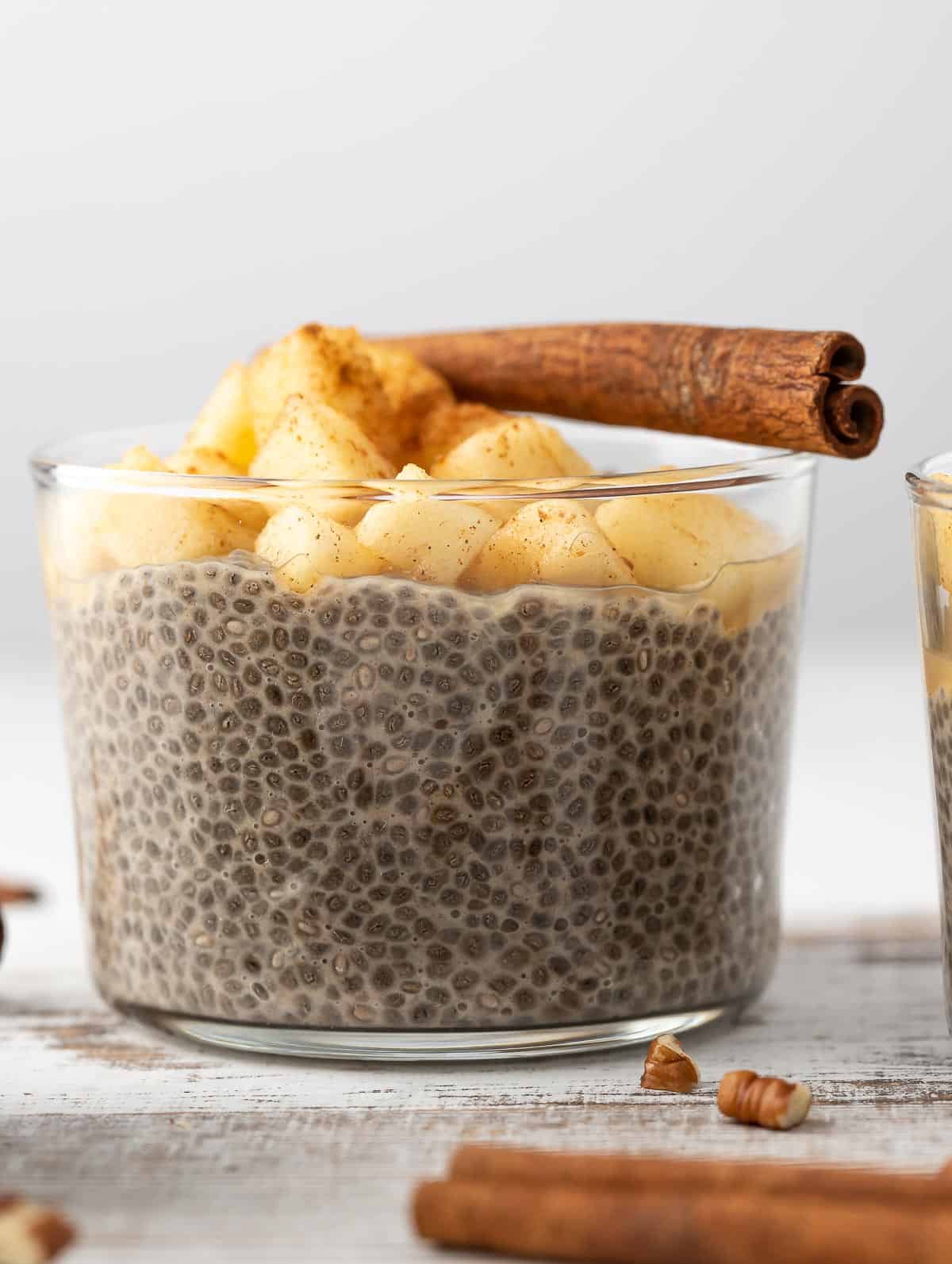 Overnight Chia Pudding topped with apples and a cinnamon stick.