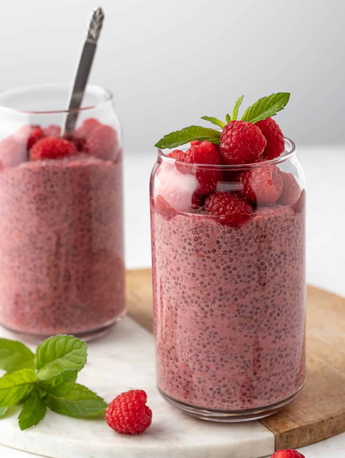 Raspberry Protein Chia Seed Pudding, topped with fresh raspberry and mint leaf on top served on a marble tray