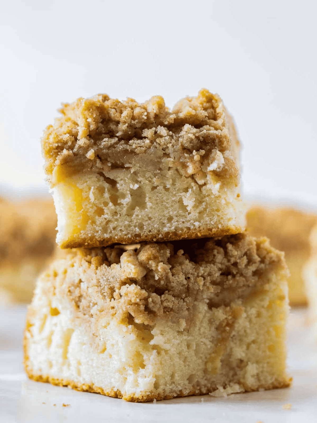 Two pieces of apple cake with crumb topping stacked for serving.
