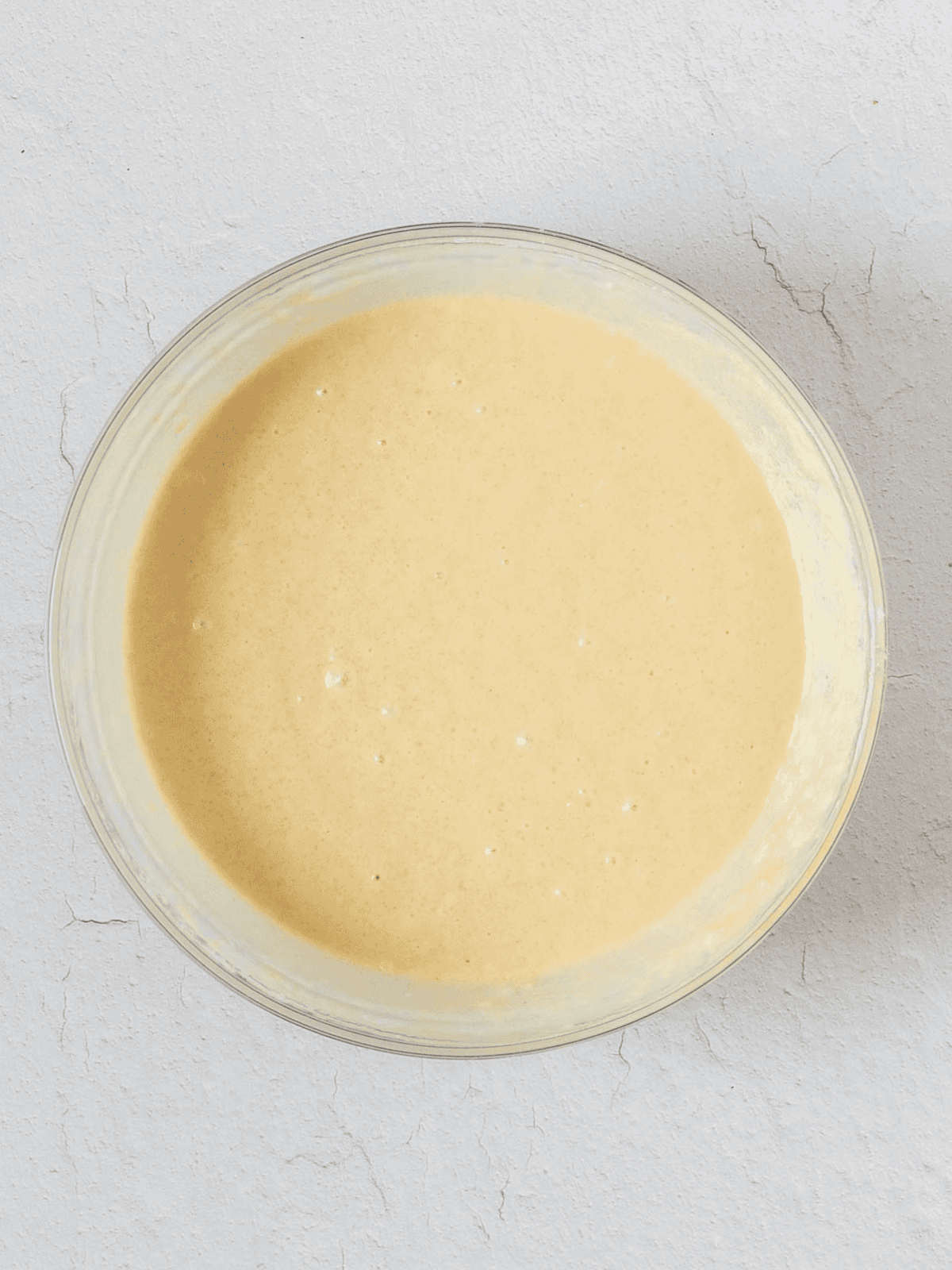 Smooth cake batter mixed in a large glass bowl.