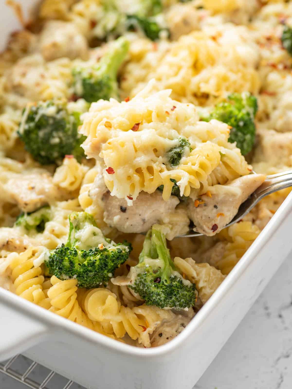 a spoon scooping up some chicken broccoli and pasta bake
