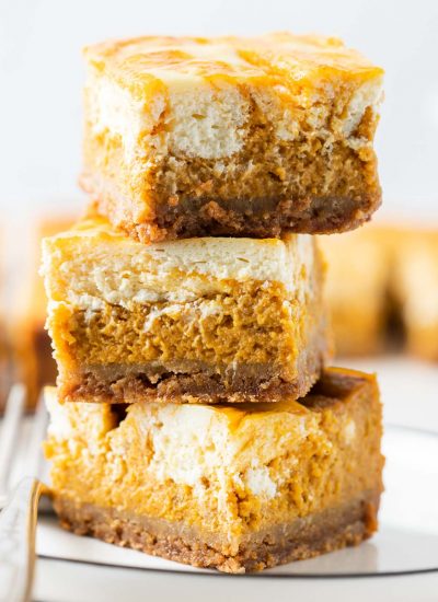 3 stacks of the pumpkin cheesecake bars in a close up shot