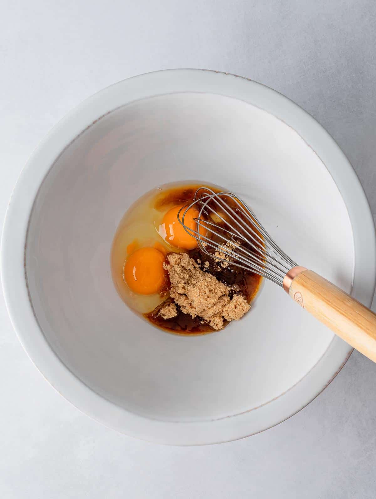 Wet ingredients added to a bowl with a whisk.