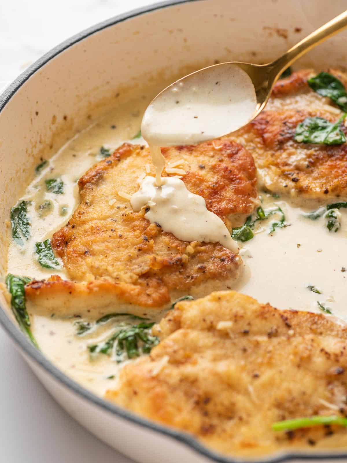 creamy florentine sauce being drizzles onto the chicken