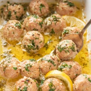 Garlic Butter Turkey Meatballs in a baking dish with a spoon scooping one.