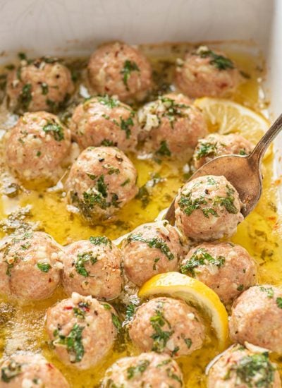 Garlic Butter Turkey Meatballs in a baking dish with a spoon scooping one.