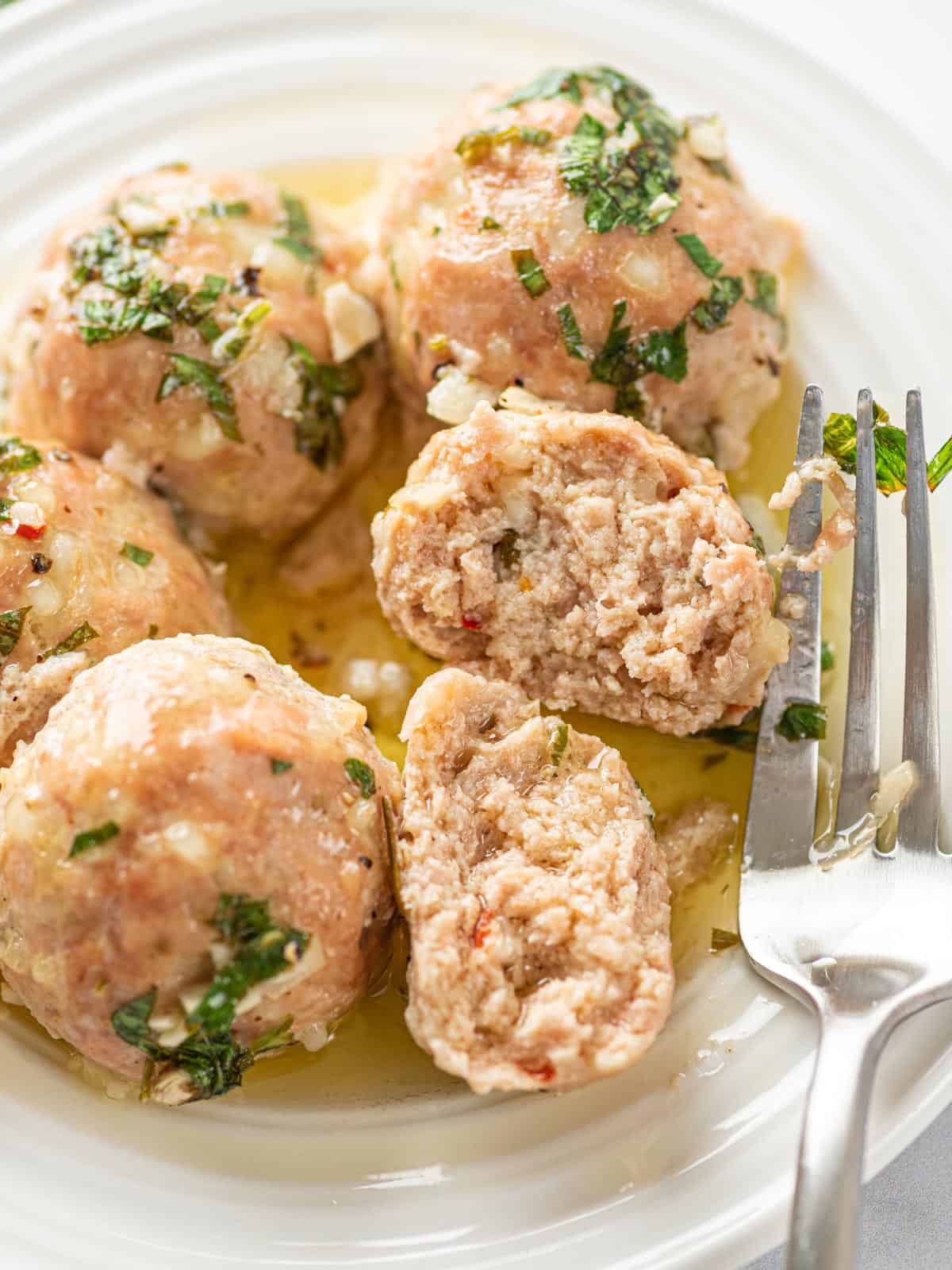 Meatballs on a plate with one meatball cut in half.