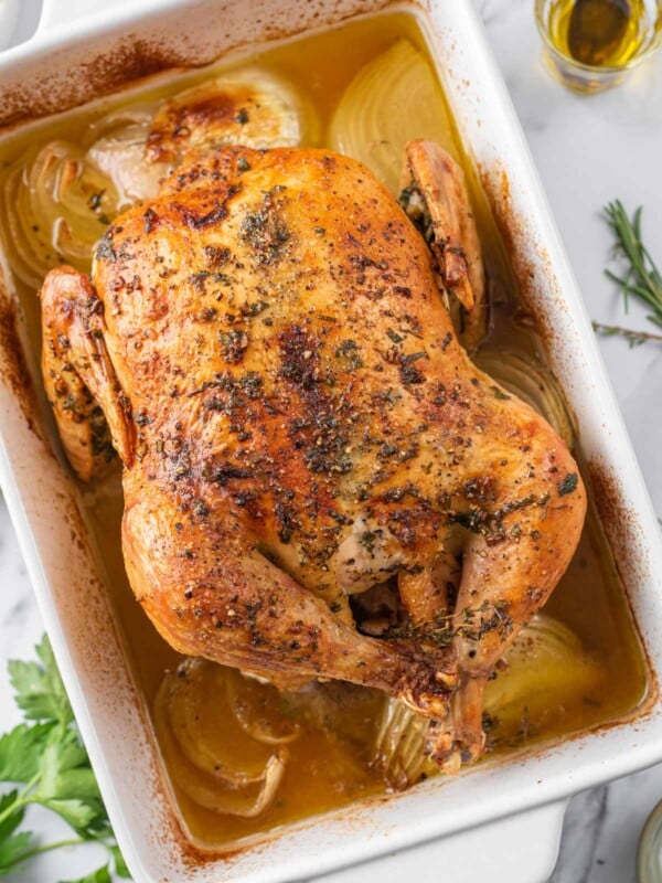 A whole roasted baked chicken in a baking dish.