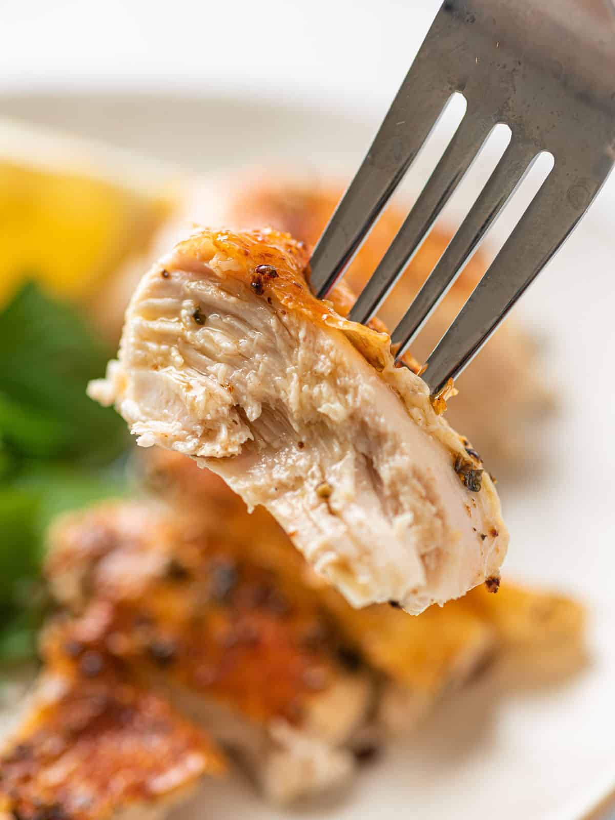 A fork with a piece chicken on it.