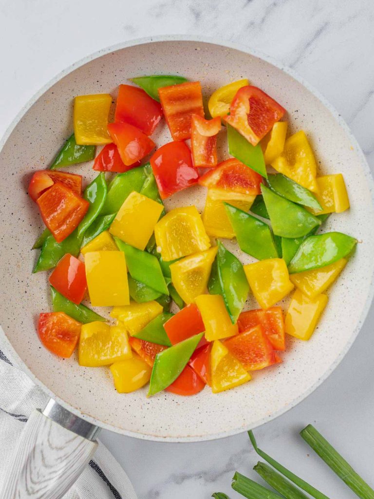 Bell peppers and snow peas in a pan.