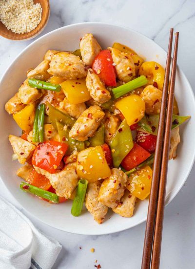 A plate of Szechuan chicken with chopsticks on the side.